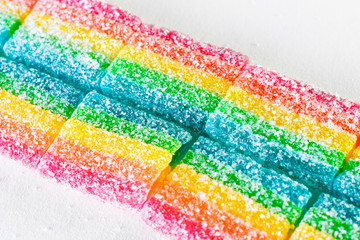 road of rainbow candies sprinkled with sugar on a white background