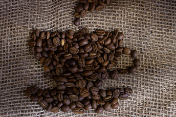 Fototapeta premium coffee beans laid out in the shape of a cup of coffee on a rough burlap