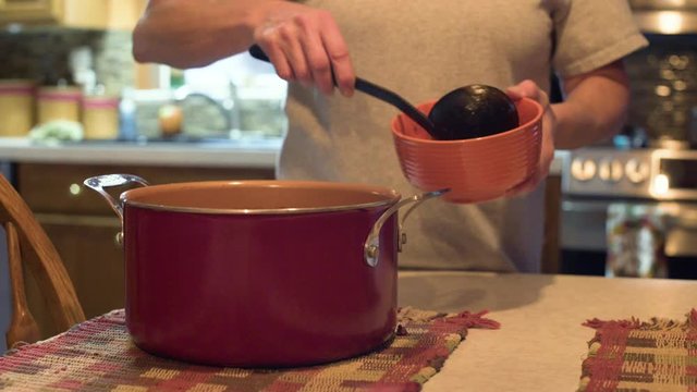 Scooping chili out of pot and into a bowl