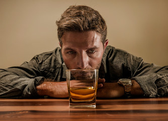 desperate alcoholic man . depressed addict isolated in front of whiskey glass trying not drinking...