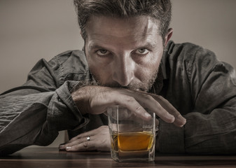 desperate alcoholic man . depressed addict isolated in front of whiskey glass trying not drinking in dramatic expression suffering alcoholism and alcohol addiction problem