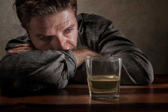 desperate alcoholic man . depressed addict isolated in front of whiskey glass trying not drinking in dramatic expression suffering alcoholism and alcohol addiction problem