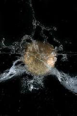 Sph&egrave;re dor&eacute;e plongeant dans l'eau, sur fond noir