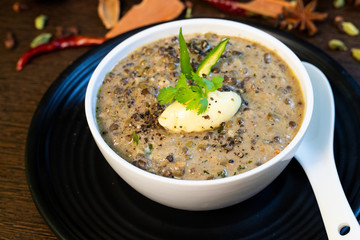 Dal makhani or butter daal makhni served in bowl, Garnished with Indian spices and coriander leaf on wooden background