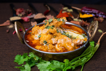 Close up view of a delicious chicken curry masala in bowl garnished with coriander leaf and with Indian spices