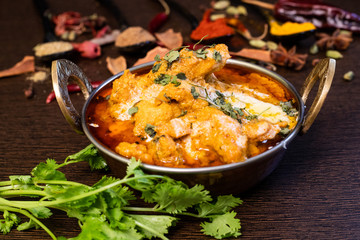 Close up view of a delicious chicken curry masala in bowl garnished with coriander leaf and with Indian spices