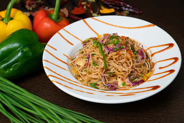 Vegetarian Schezwan Noodles or Vegetable Hakka Noodles or Chow mein in white bowl at dark background and garnished with fresh Vegetables and Indian spices. Fast food concept with Copy space.