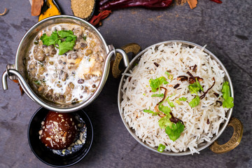 Dal makhani or butter daal makhni served with jeera rice and gulab jamun for dinner, Decorated with Indian spices and coriander leaf on wooden background