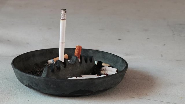 time lapse of a cigarette kept upright on a black ash tray as it burns away
