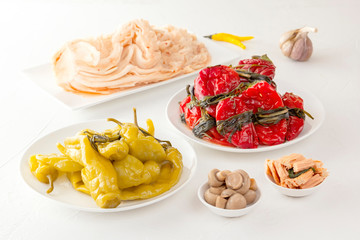 Traditional Korean fermented food - red hot peppers with greens, yellow salted peppers and kimchi cabbage on a white table