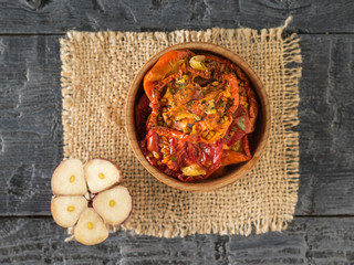 A bowl of dried tomatoes and garlic on a piece of burlap. Vegetarian food. Flat lay.