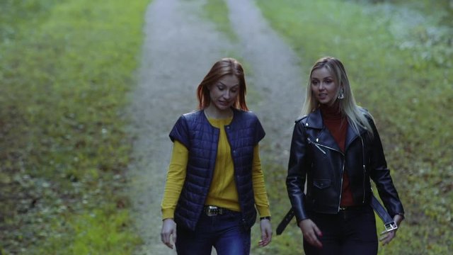 Two attractive girls having chat and walk outdoors spotting something