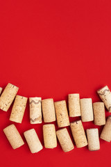 Used wine corks on red paper background with copy space. Top view with wooden corks from bottle of wine. Flat lay.