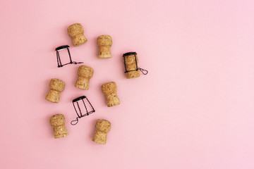 Wooden corks and muselets from bottle of champagne on pink colored background with empty space for your text. Celebration concept. Top view and flat lay.