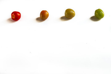 4 fresh organic tomatoes from green to red on a white background