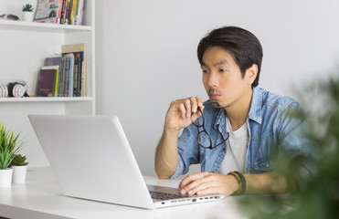 Asian Casual Businessman or Freelancer Working with Laptop in Home Office