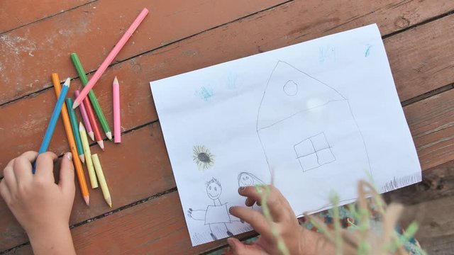 Child draws a pencil drawing of the house and his family. New home.