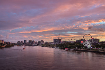 Brisbane City River At Sunset With A Dramatic Pink Pastel Sky With Buildings And The Ferris Wheel In The Distance