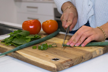 Persons Hands Cutting Up Fresh Healthy Vegetables In A Kitchen On A Timber Chopping Board