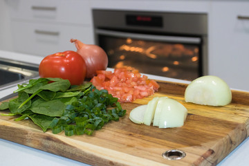 Chopping Board On A Kitchen Bench Full Of Fresh Healthy Vegetables And A Oven In The Background
