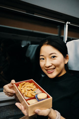 Asian girl is showing Bento, Japanese meal in box, for her journey.