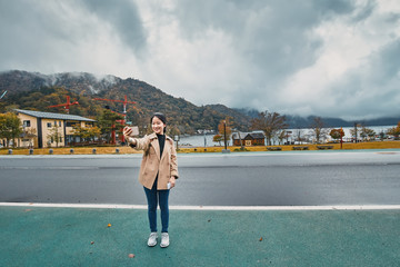 Asian girl using smartphone to selfie at Chuzenji Lake, Nikko, Japan