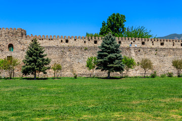 Spruce trees near ancient stone fortress wall inside of Svetitskhoveli church complex in Mtskheta, Georgia