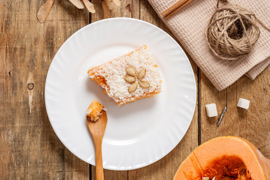 Slice of fresh homemade pumpkin pie and semolina on a white plate on a wooden background. . A Thanksgiving or holiday treat. Traditional autumn dish. Top view