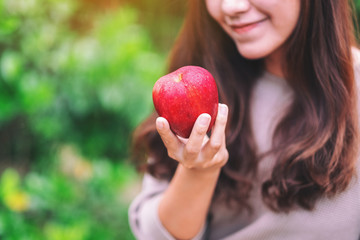 A beautiful woman holding a fresh red apple to eat