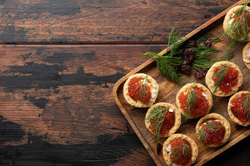 Red caviar in tartalets on a wooden table