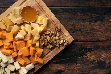 various cheeses with honey on the wooden board