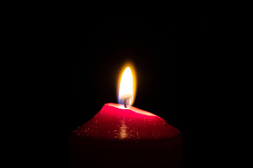 Brennende rote Kerze als Weihnachtskerze oder Weihnachtsdekoration erleuchtet die Dunkelheit und schwarze Nacht in der Adventszeit