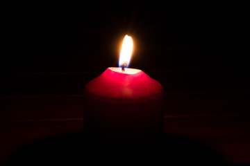 Brennende rote Kerze als Weihnachtskerze oder Weihnachtsdekoration erleuchtet die Dunkelheit und...