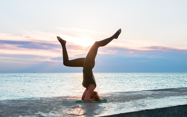Fototapeta na wymiar unrecognizable senoir woman with beautiful body doing yoga splits at sunrise on the sea, silhouette of yoga poses