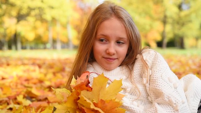 teenage girl having rest among maple trees in autumn park