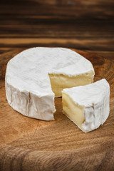 camembert cheese on wooden plate. wood background closeup