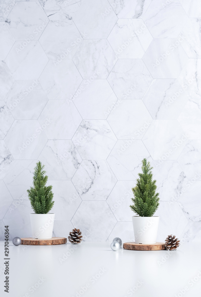 Poster christmas tree with pine cone,decor xmas ball on wood log at white table and marble tile wall background.clean minimal simple style.holiday still life with space to adding text