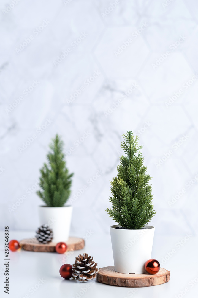 Poster christmas tree with pine cone and decor xmas ball on white table and marble tile wall background.clean minimal simple style.holiday still life mockup banner with space to adding text