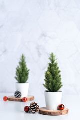 christmas tree with pine cone and decor xmas ball on white table and marble tile wall background.clean minimal simple style.holiday still life mockup banner with space to adding text