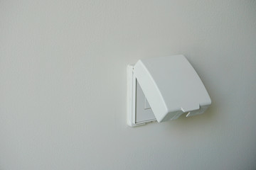 White power outlet cover, plug housing or plug socket with waterproof cover on white wall .Electric safety concept.