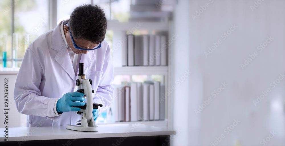 Wall mural laboratory concept: scientist researching by microscopy technique in laboratory with copy space.