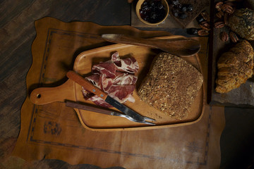 bread sticks and slice of meat on wooden board over a dark background. Top view