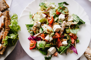 Caesar salad in a white plate at the background of the table. Close up