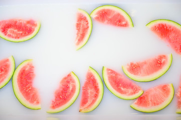 Turbid soapy water in bath with slices of watermelon. top view in full frame. The largest berry. spa with milk in the bath for rejuvenation..