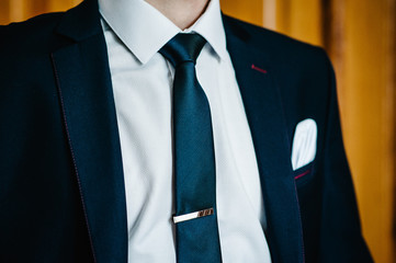 The part man in a suit, shirt, tie, silver buckle on tie. stylish classic menswear. A businessman prepares in the morning for a business day or groom in a wedding.