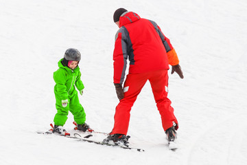 little girl learns to ski with the help of an adult