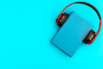 Blue book with headphones on blue background. Top view. Space for text.