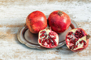 Pomegranates, whole and in the context, red and ripe on the wooden natural table.Food concept.