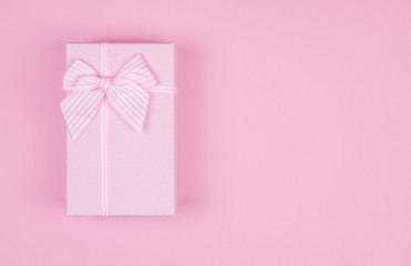 Pink rectangular gift box with pink ribbon on pink background. gift for March 8, Valentine's day, birthday. Top view. Copy space