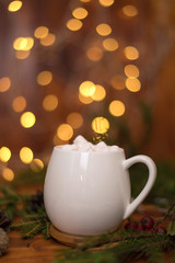 Cacao drink in a white cup with marshmallow on the background of bokeh lights, Hot Christmas drink